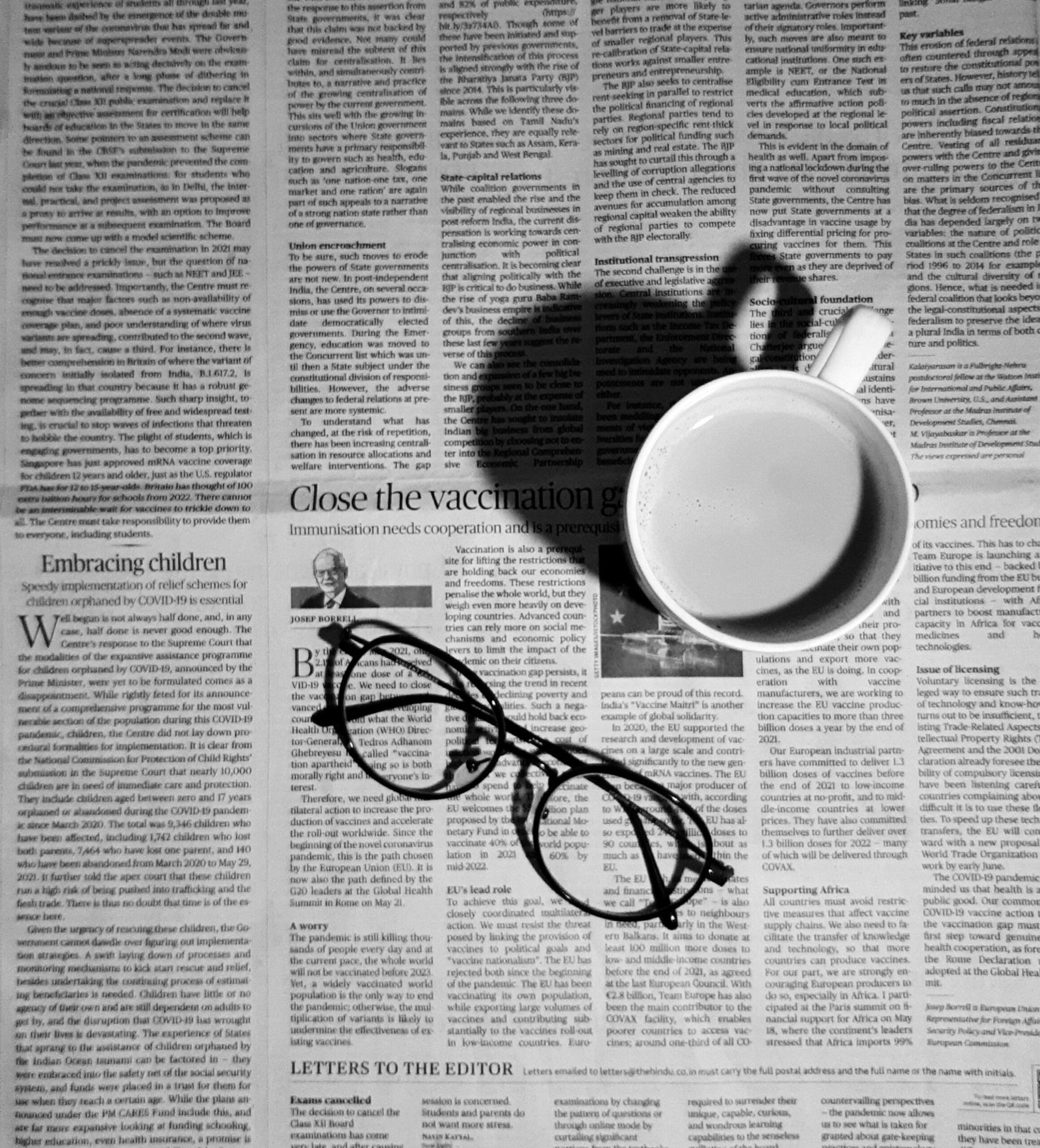 a cup of coffee and a pair of glasses on a newspaper